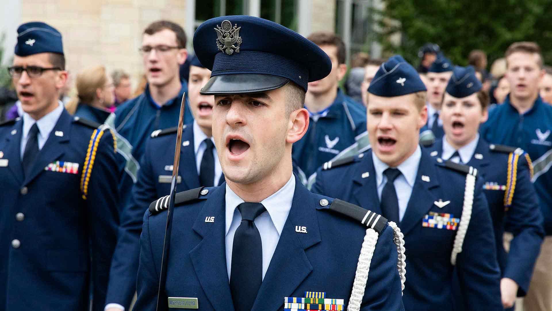 Cadets marching and shouting cadence while in formation during a Saint Thomas homecoming parade.