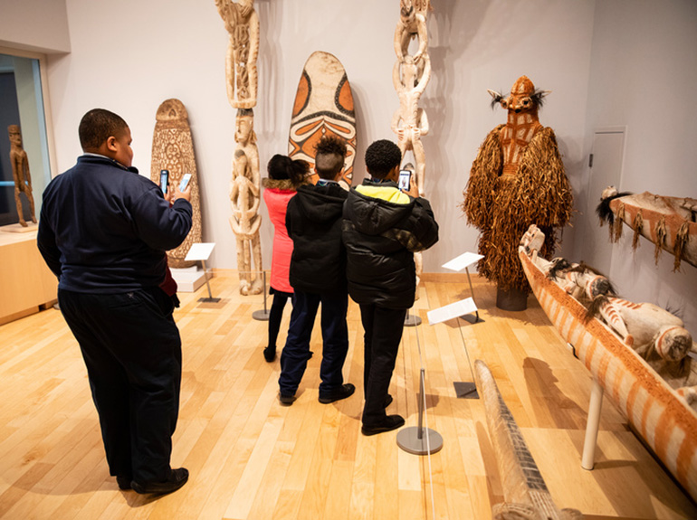 A group of children take pictures of artifacts in the Asmat Museum.