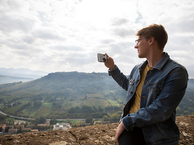 A student taking a picture with a cell phone of the Italian countryside.