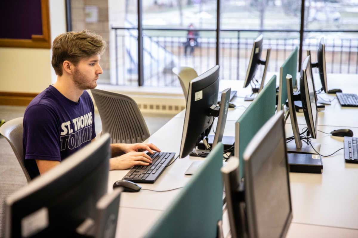 St. Thomas student working on computer in library