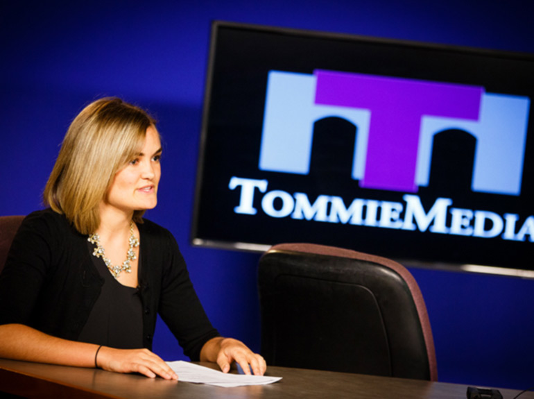 A student speaks into a camera on set for Tommie Media. 