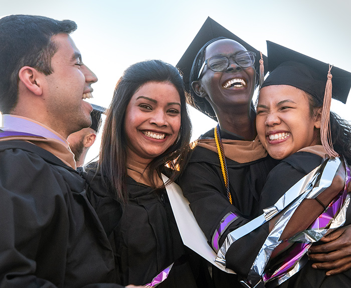 St. Thomas students smiling and hugging after Graduate Commencement