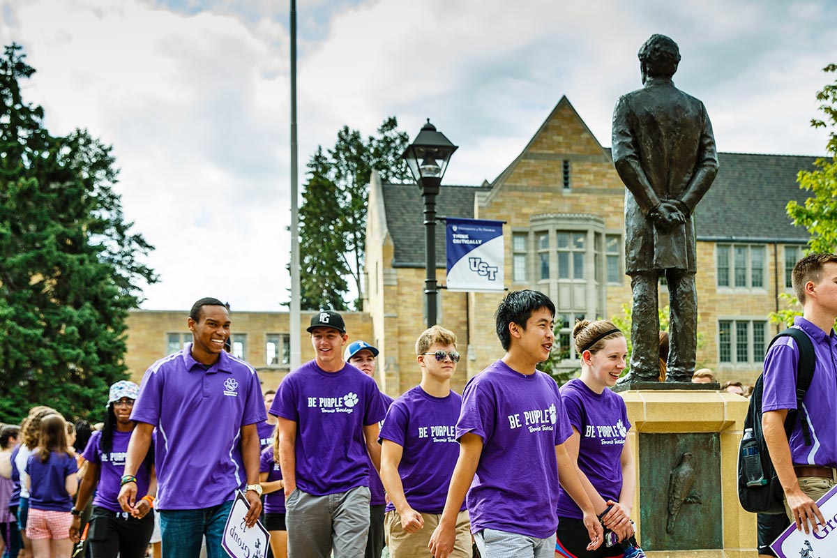 Students marching past the statue of John Ireland on campus.