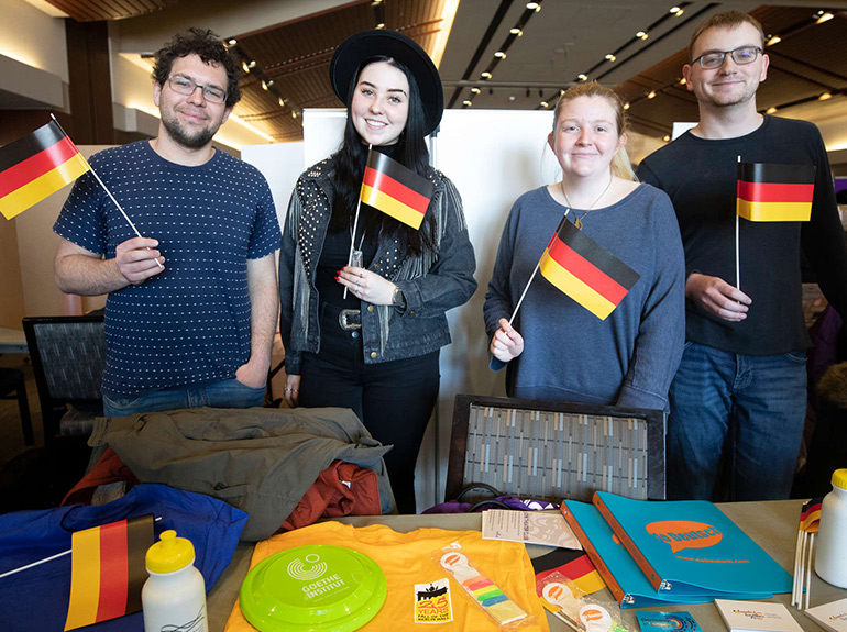 Members of the German Club pose for a photo holding tiny German flags at the Spring Activities Fair.