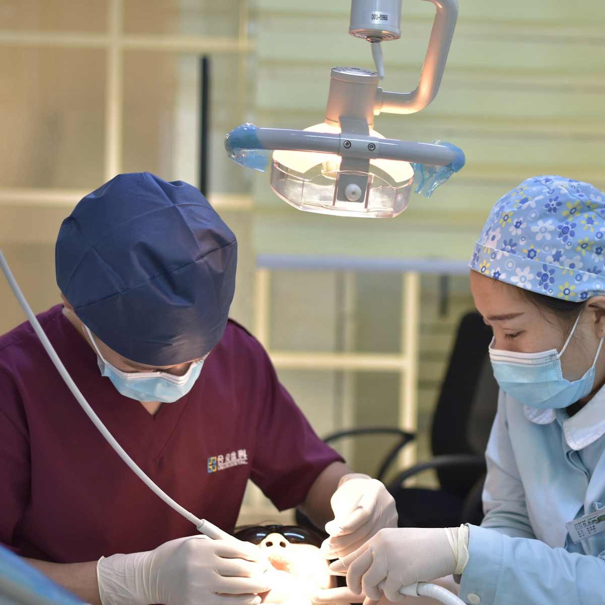 Stock image of a dentist and dental hygienist examining a patient’s mouth. 