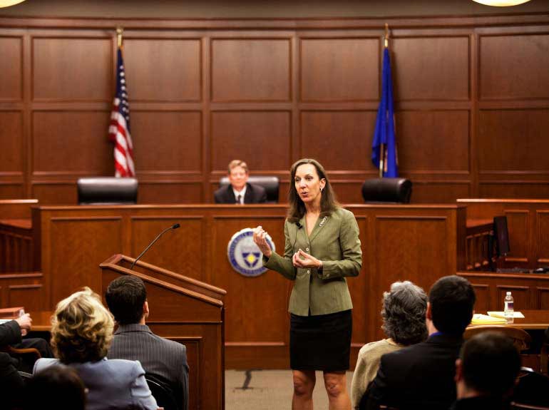 A woman speaks in front of a courtroom during a mock trial.