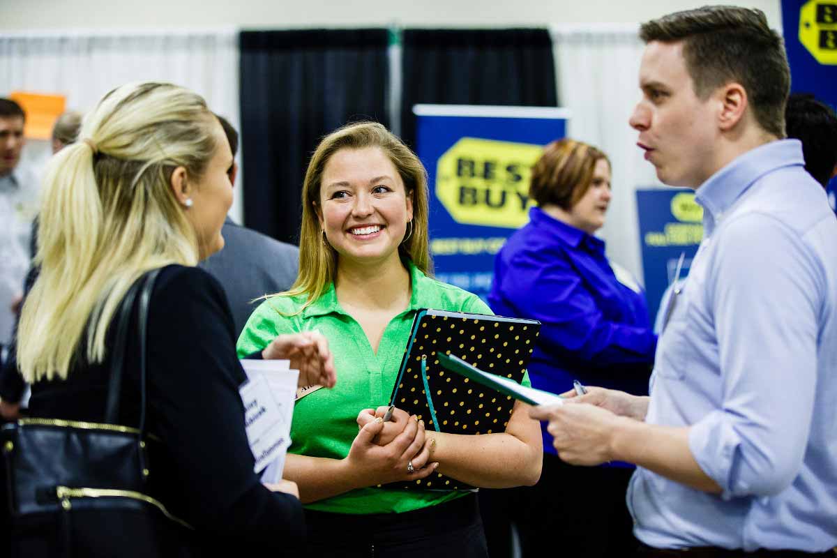 Student smiling as she talks to two fellow students at the Minnesota Private College Job Fair. 
