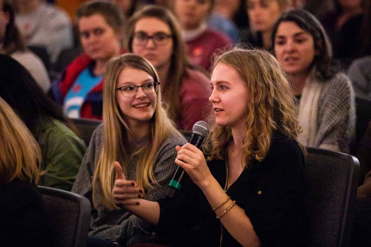 A female student holds a microphone and asks a question during an event on the St. Thomas campus hosted by the Luann Dummer Center for Women. 