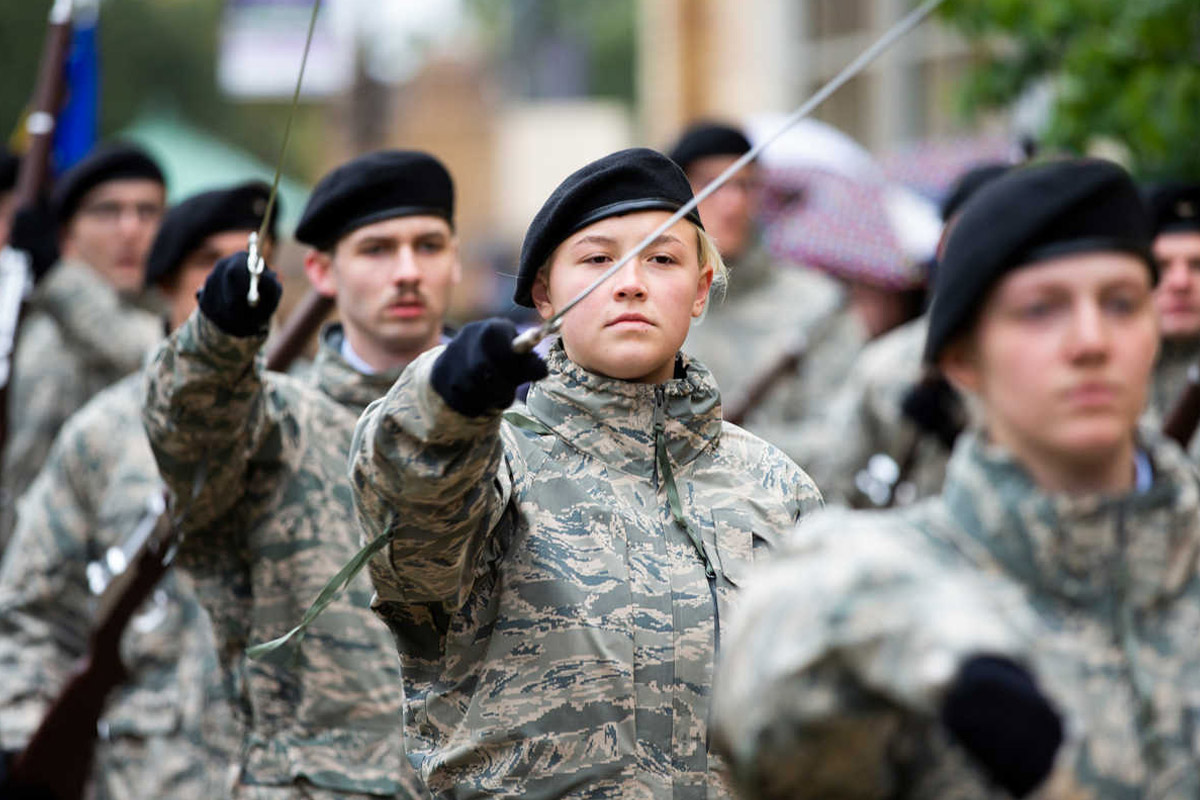 Several cadets perform military saber honors during a Saint Thomas homecoming parade.