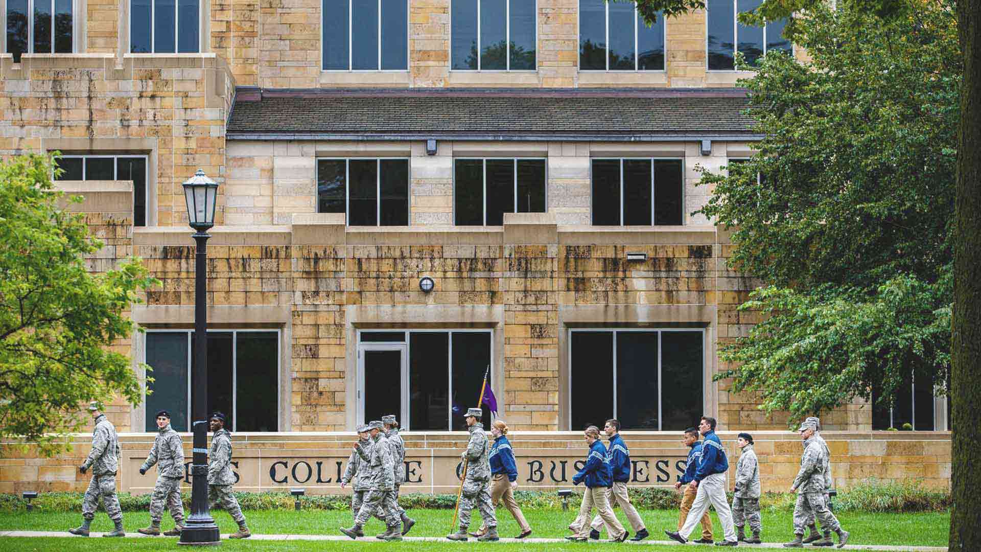 A group of cadets walk past Saint Thomas McNeely Hall.