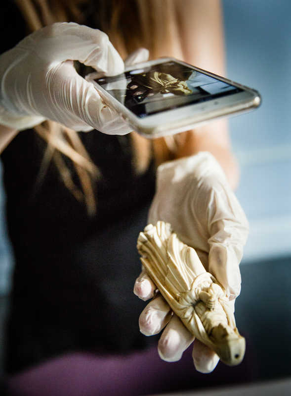 A student uses her smart phone to document a piece of a sculpture 