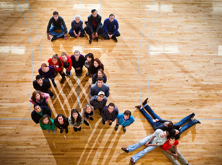 Students and faculty of Gamma Iota Sigma pose in a gymnasium. 