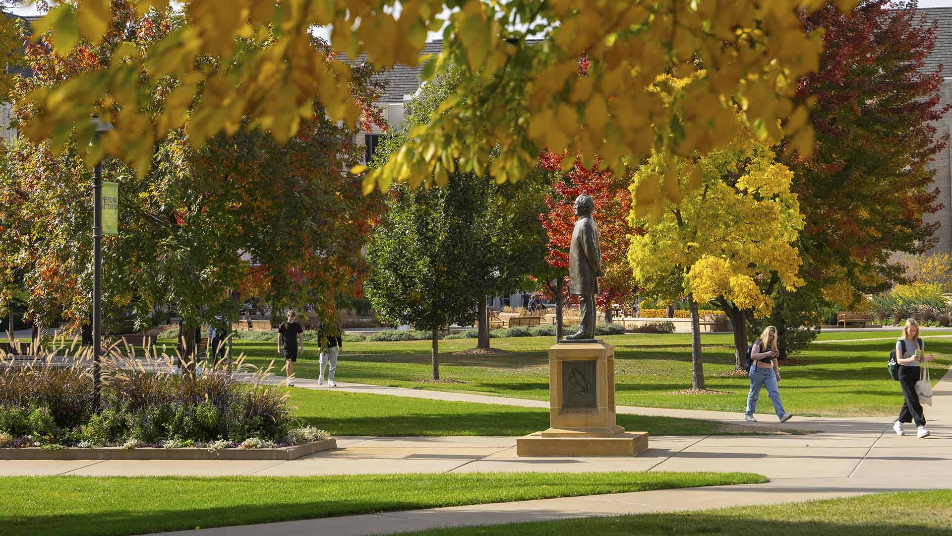 Statue of Archbishop John Ireland on the St. Thomas campus, framed by yellow-leaved trees