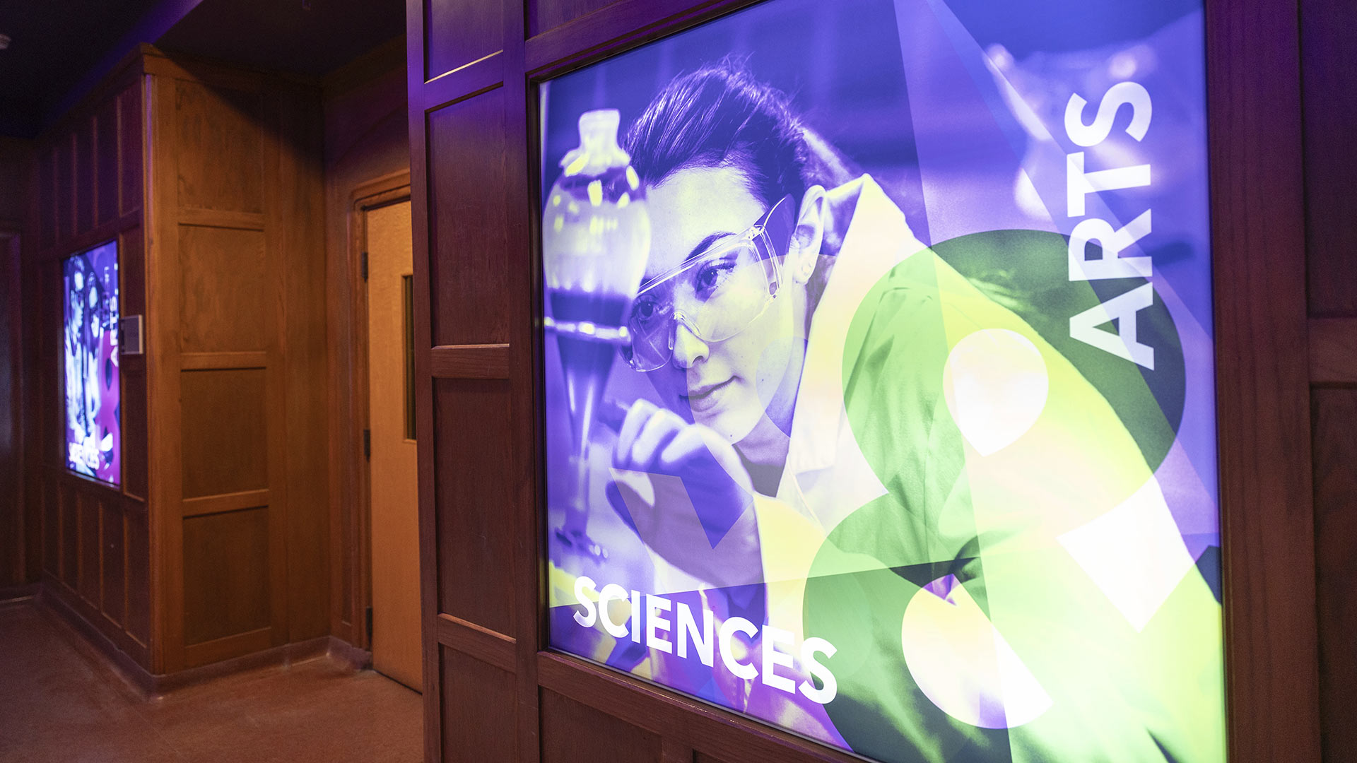 Backlit displays in the entryway of the John Roach Center show colorful photos of students in science labs