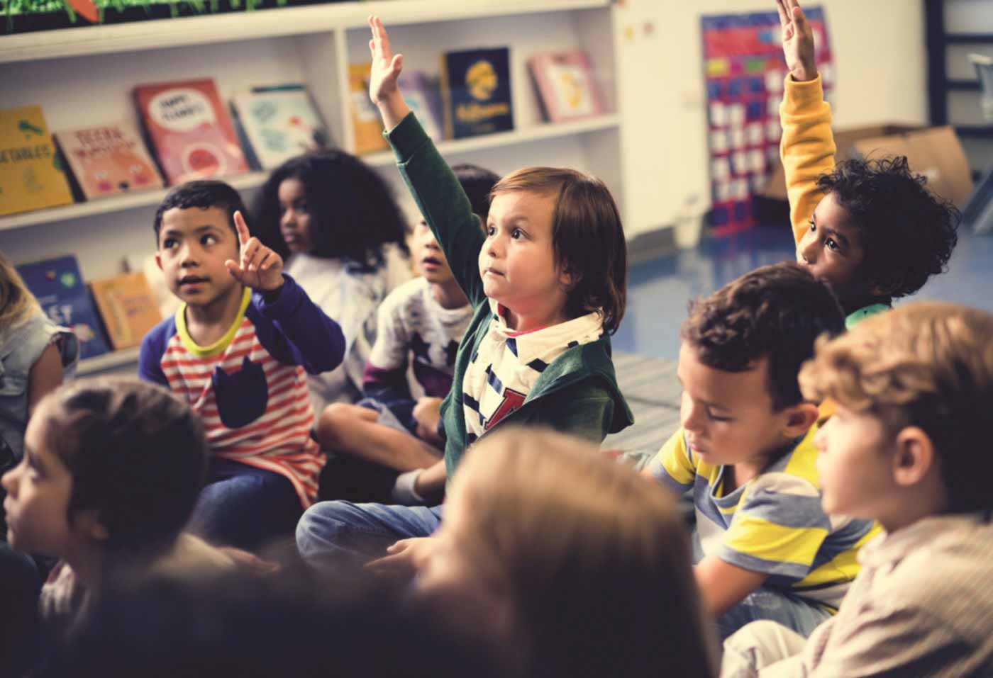 Children raise their hands to answer a question in a classroom