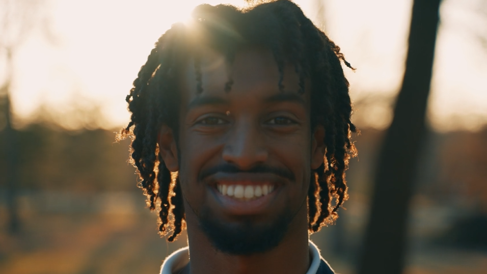 A student smiling with sunlight behind him