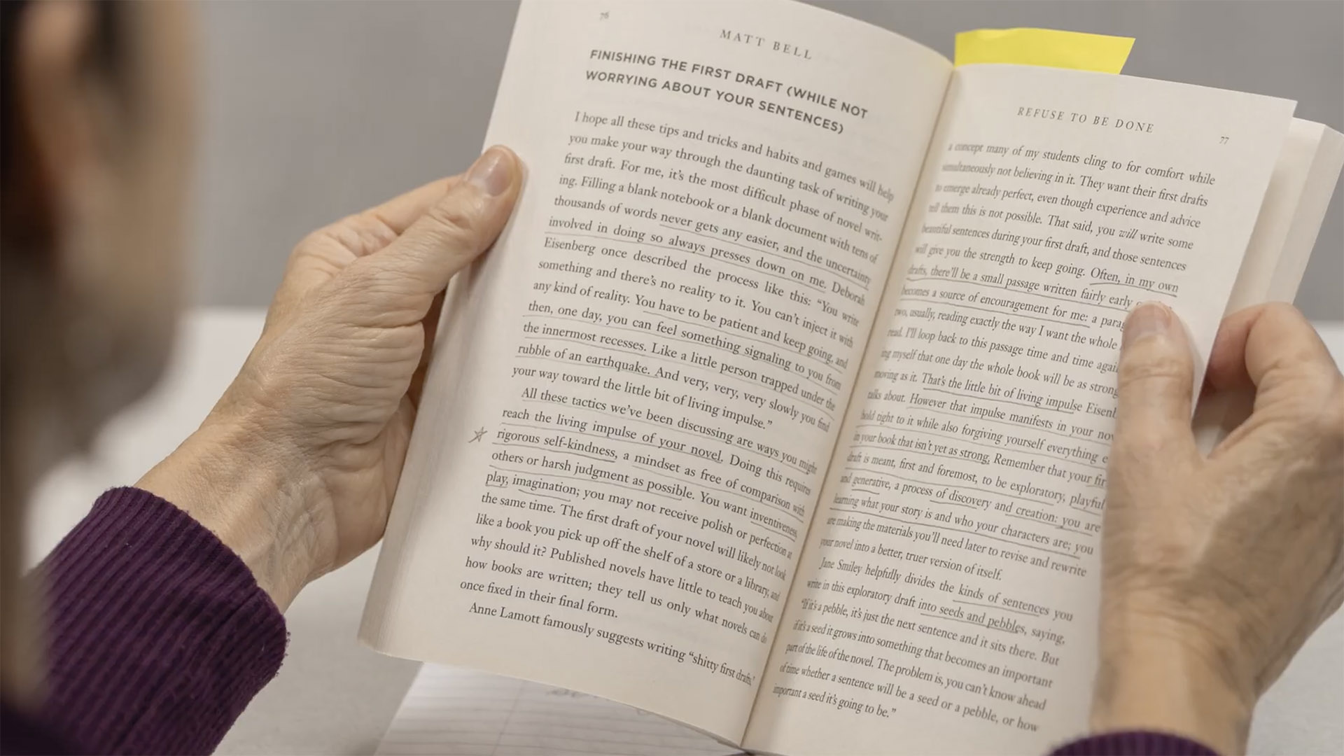 A woman holds a book that is underlined and annotated.