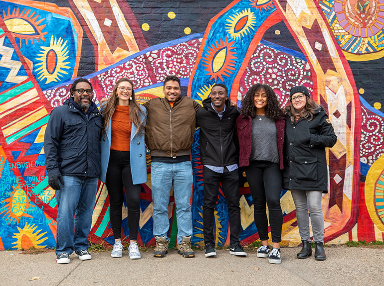 College of Arts and Sciences faculty and students in front of a mural that is part of the Midway Murals project.
