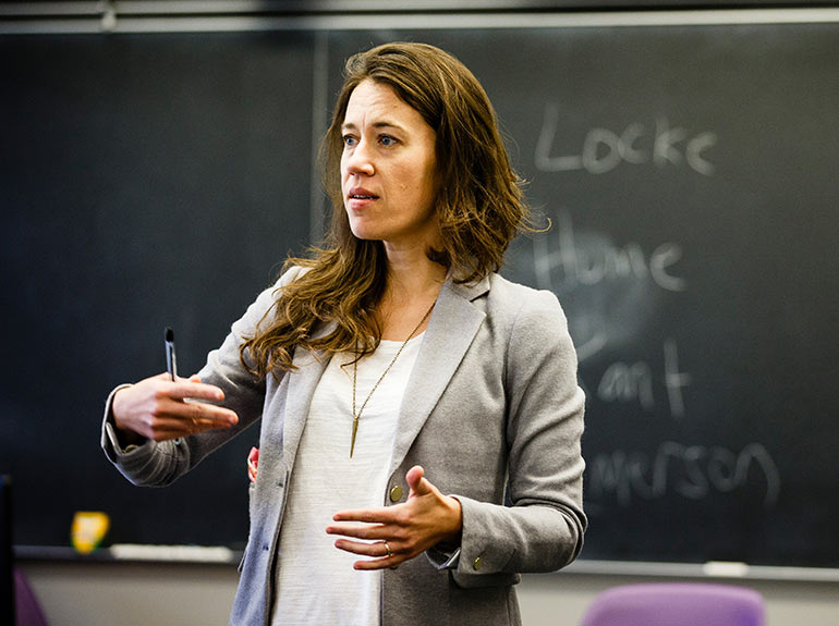 Dr. Laura Zebuhr stands in front of a chalkboard as she leads class discussion. 