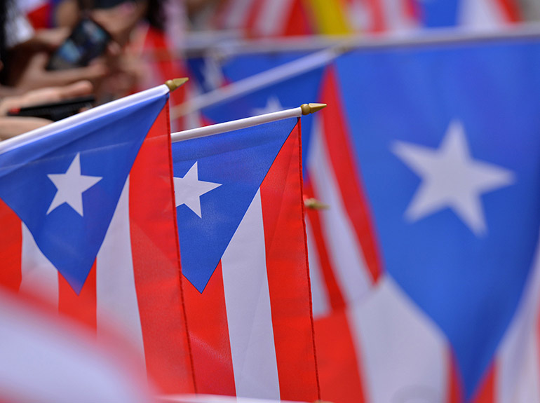 Stock image of people holding Puerto Rican flags at a parade. 