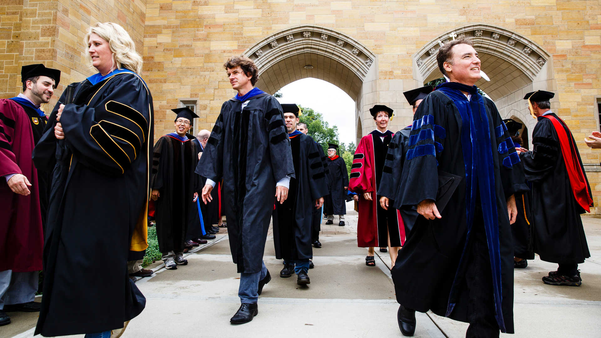 St. Thomas faculty marching through arches