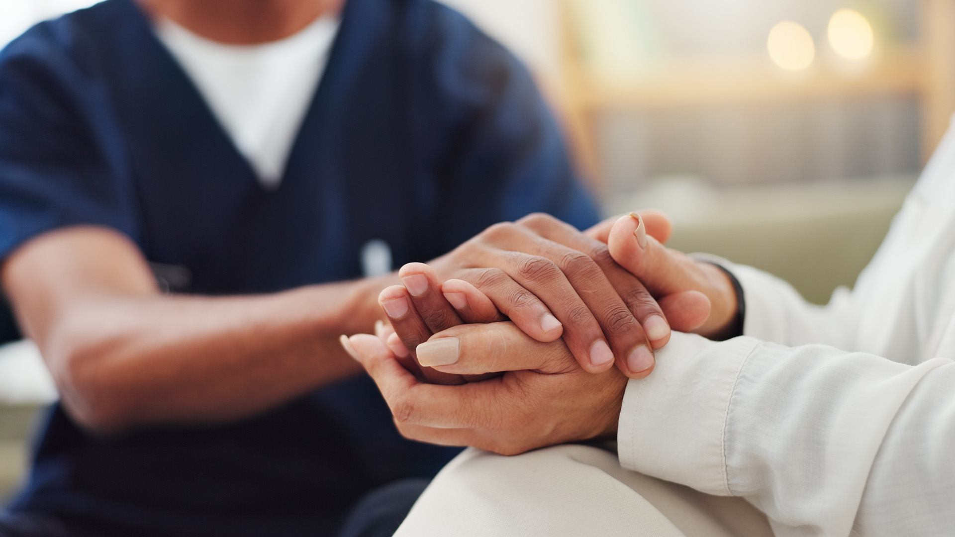 A health professional and a patient hold hands