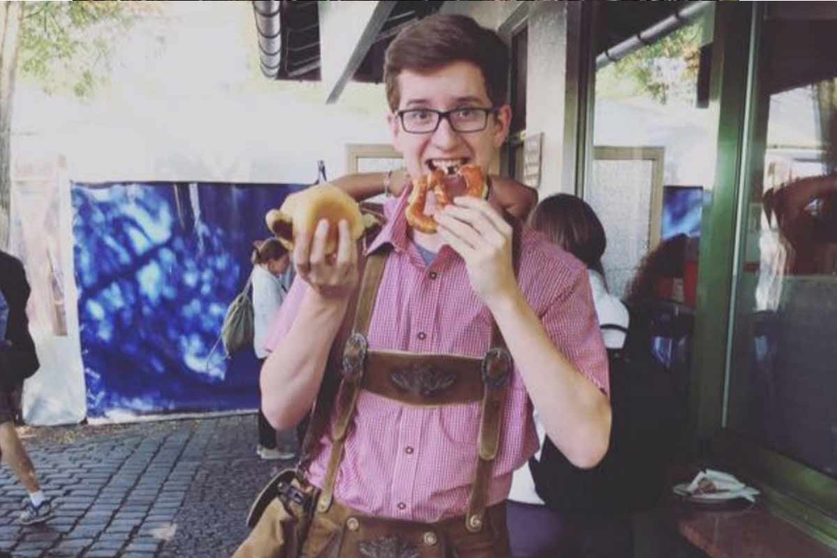 Photo of German alumnus Mitchell Sullivan eating pretzels and wearing traditional German clothing at Oktoberfest.