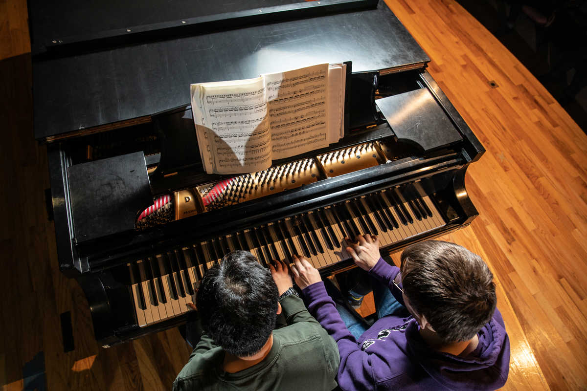 Two students playing the piano.
