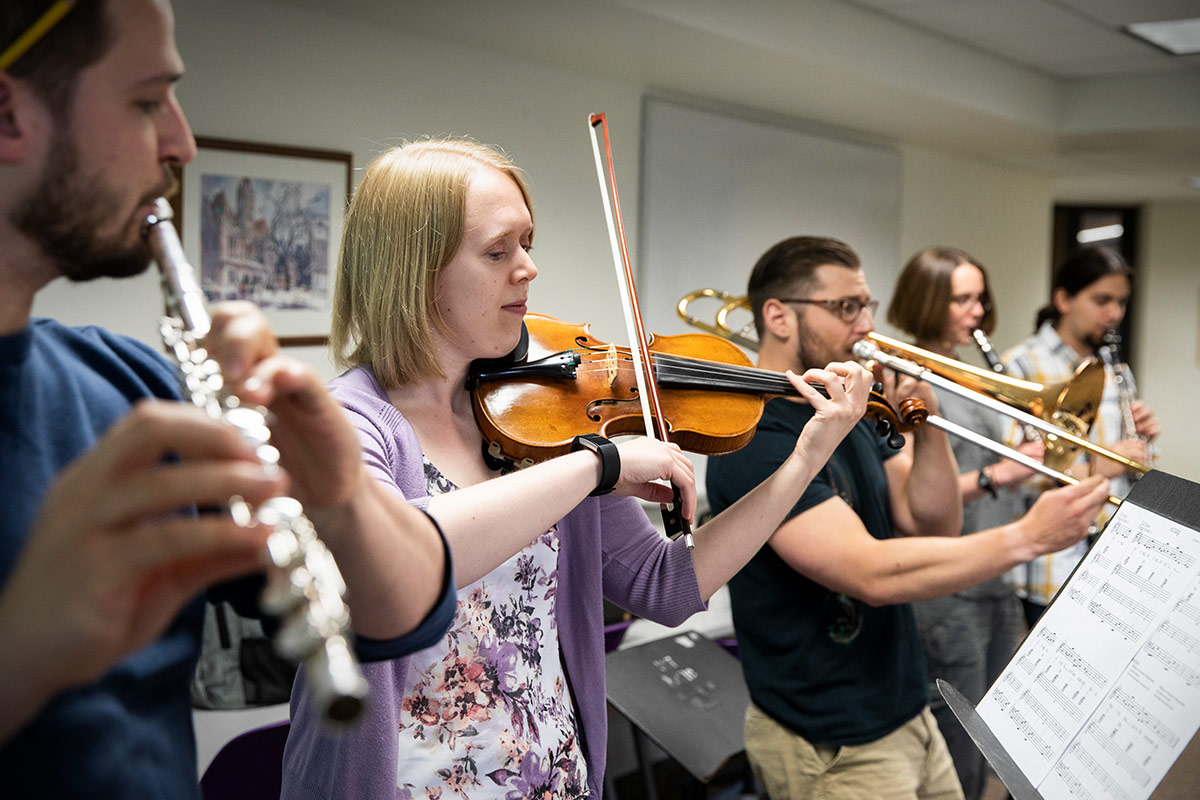 Graduate students practicing together with various instruments.