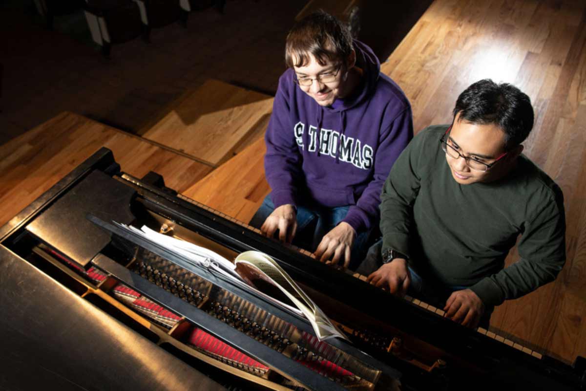 Students play the piano together.