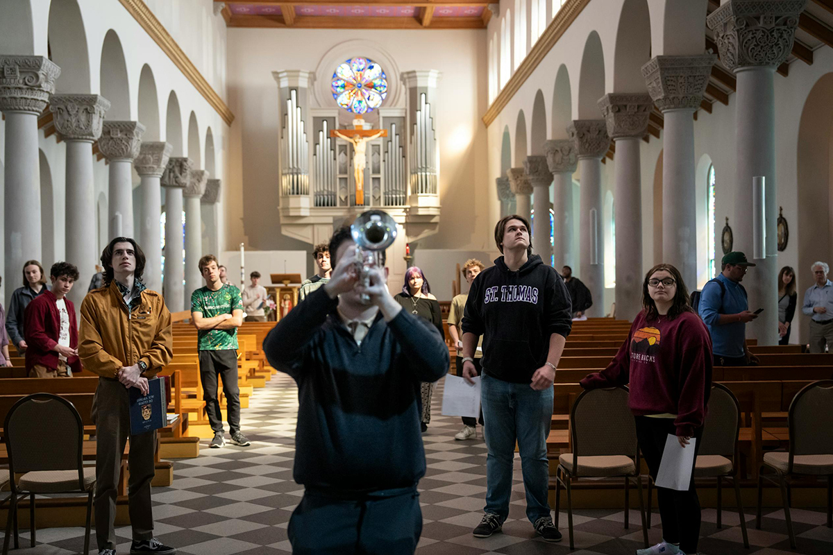 A students plays a trumpet in the chapel while classmates study the acoustics